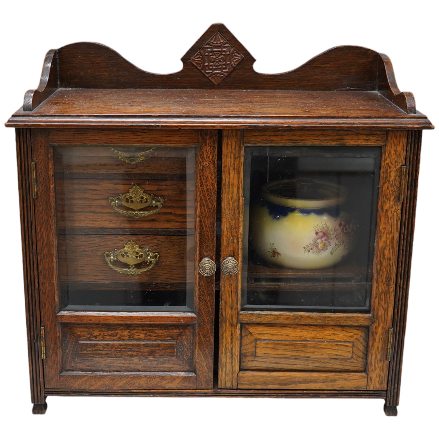 A carved oak smokers cabinet with Cartonware tobacco jar, cigar pricker and amber mouthpiece, 42cm wide. Condition - fair to good